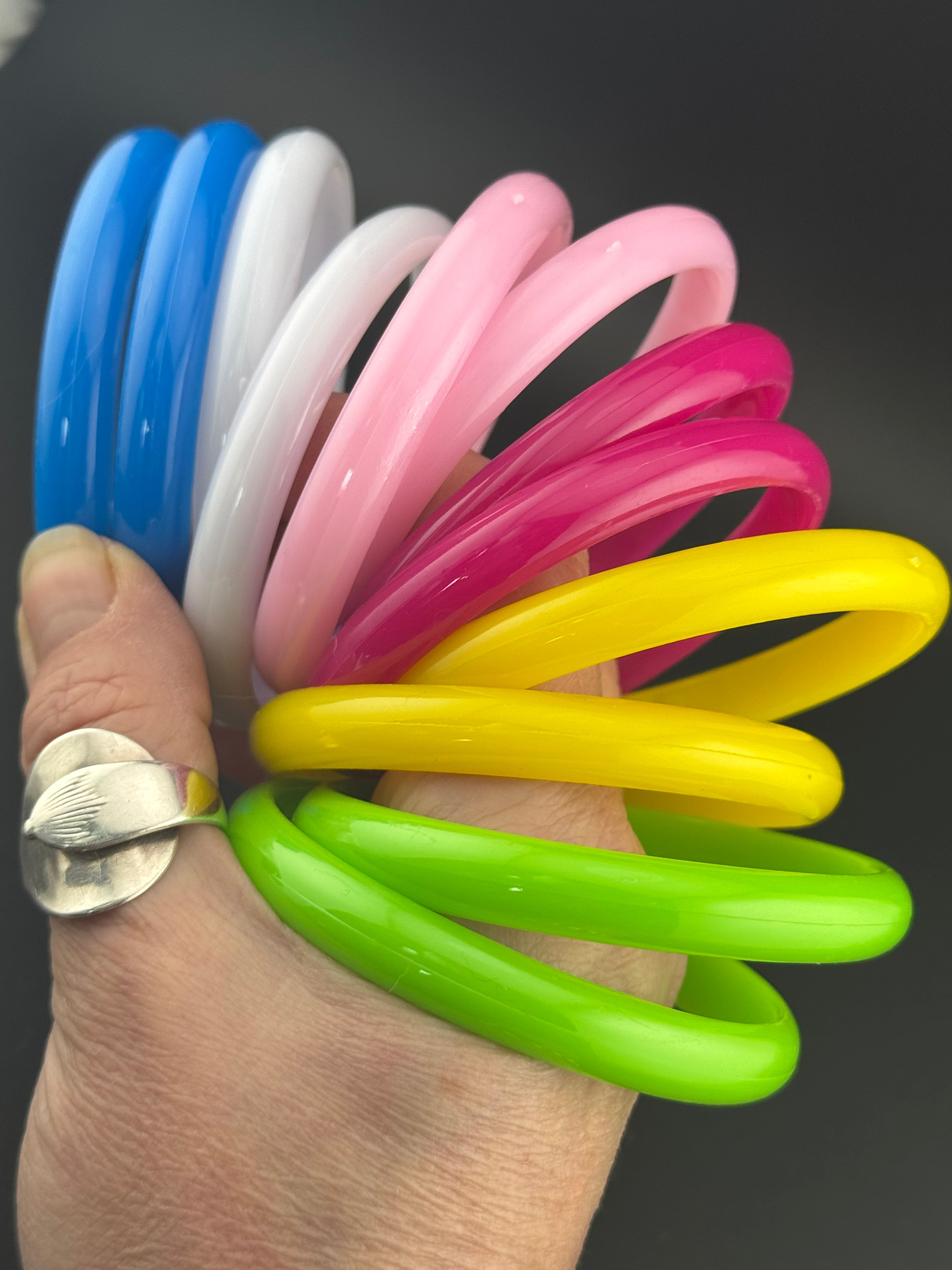 Stack of 12 coloured acrylic stacking bangles in baby pink yellow bright pink blue white green