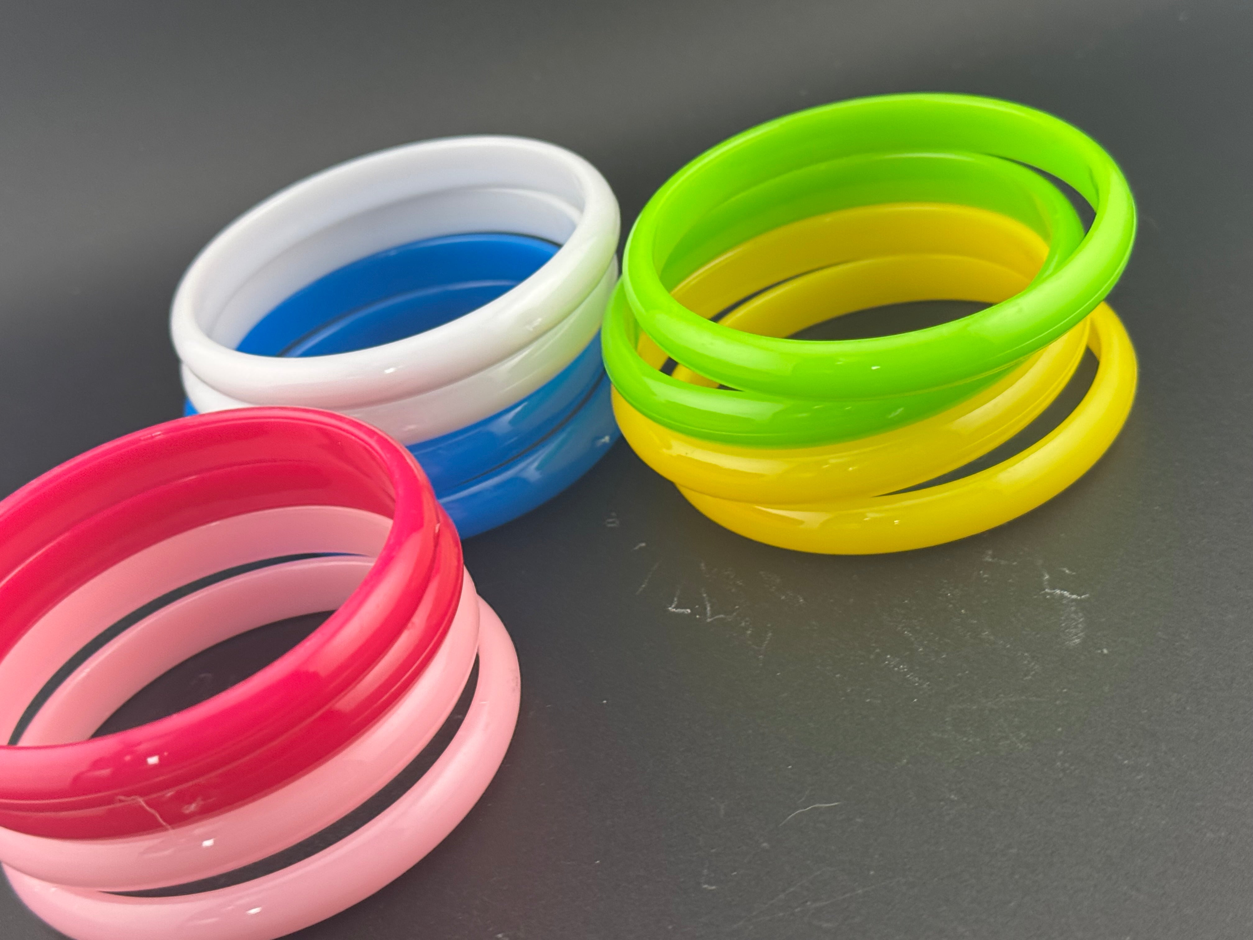 Stack of 12 coloured acrylic stacking bangles in baby pink yellow bright pink blue white green