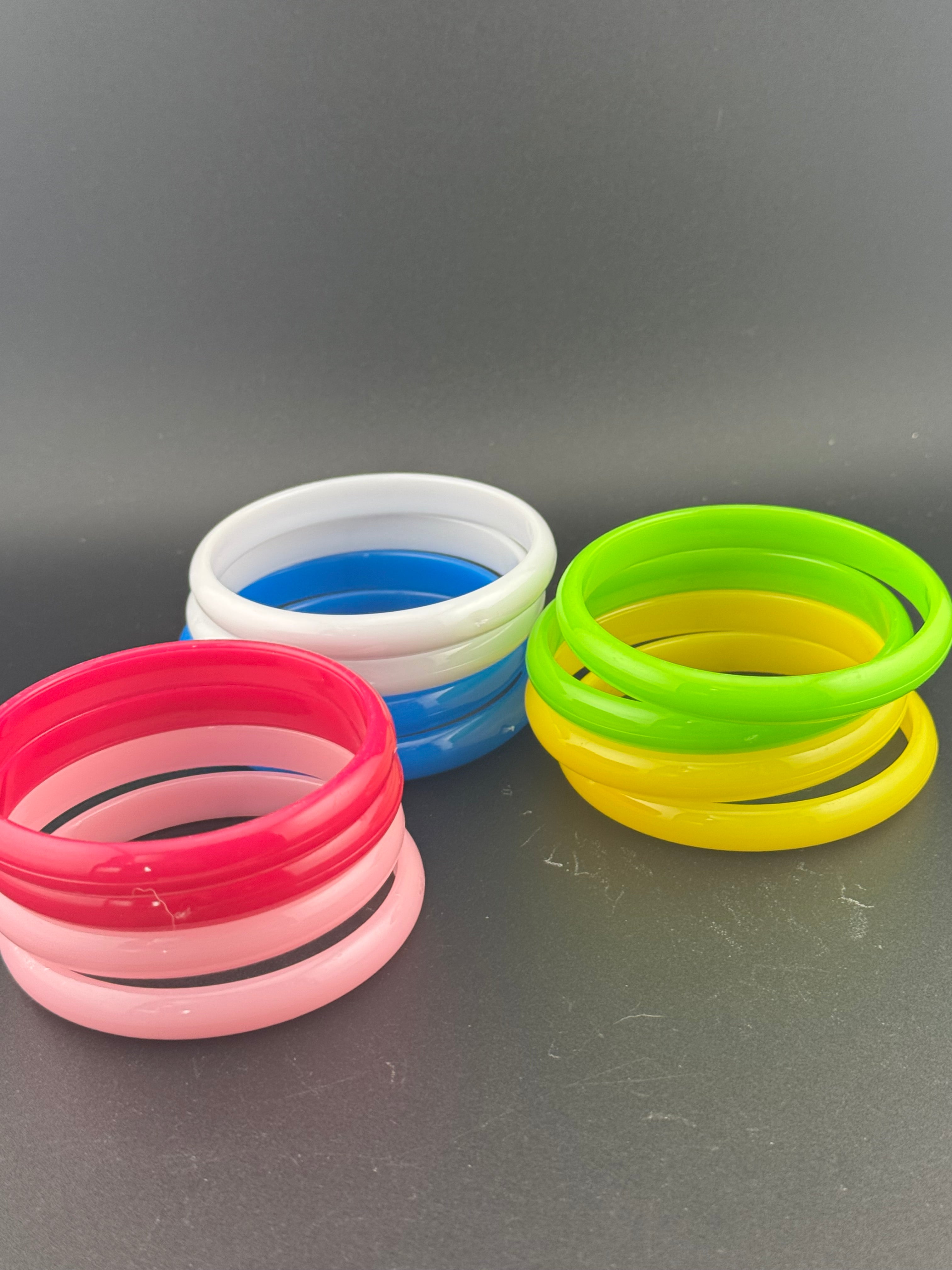 Stack of 12 coloured acrylic stacking bangles in baby pink yellow bright pink blue white green