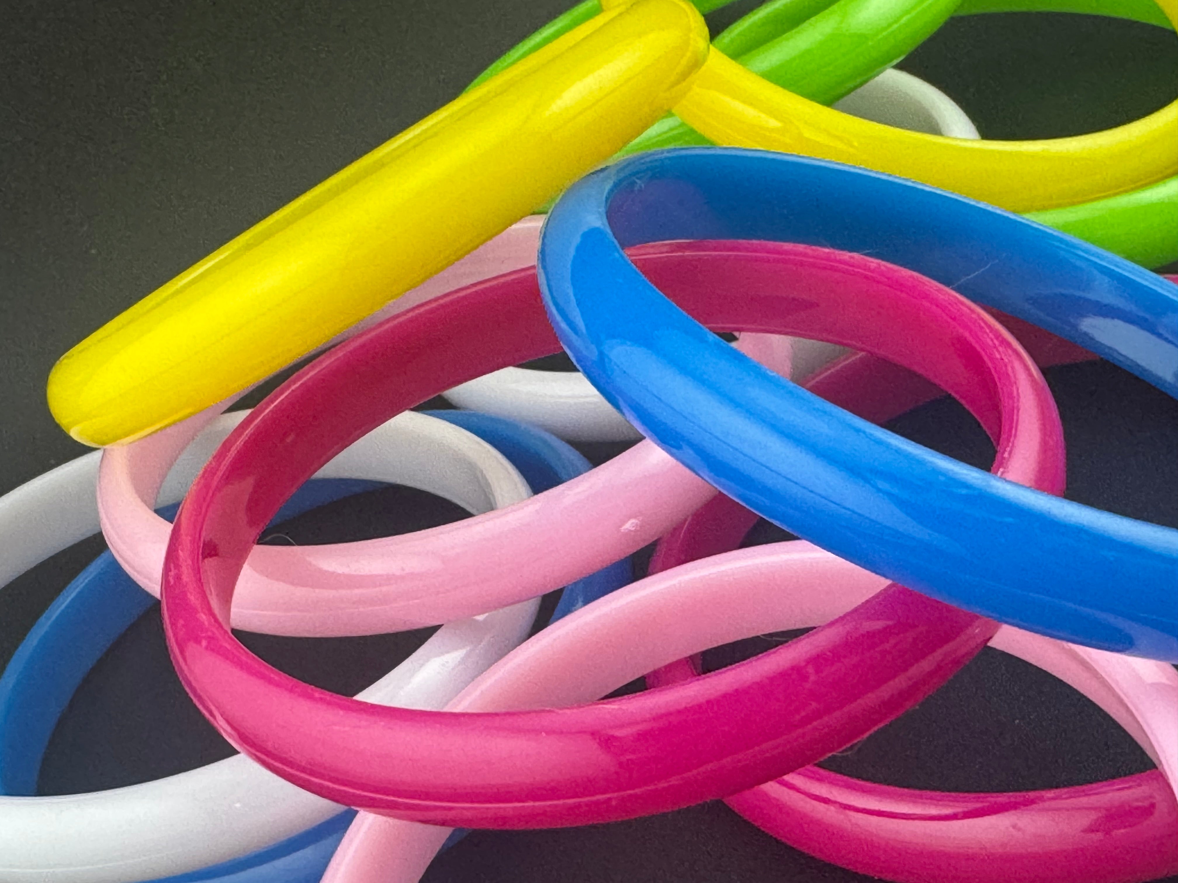 Stack of 12 coloured acrylic stacking bangles in baby pink yellow bright pink blue white green