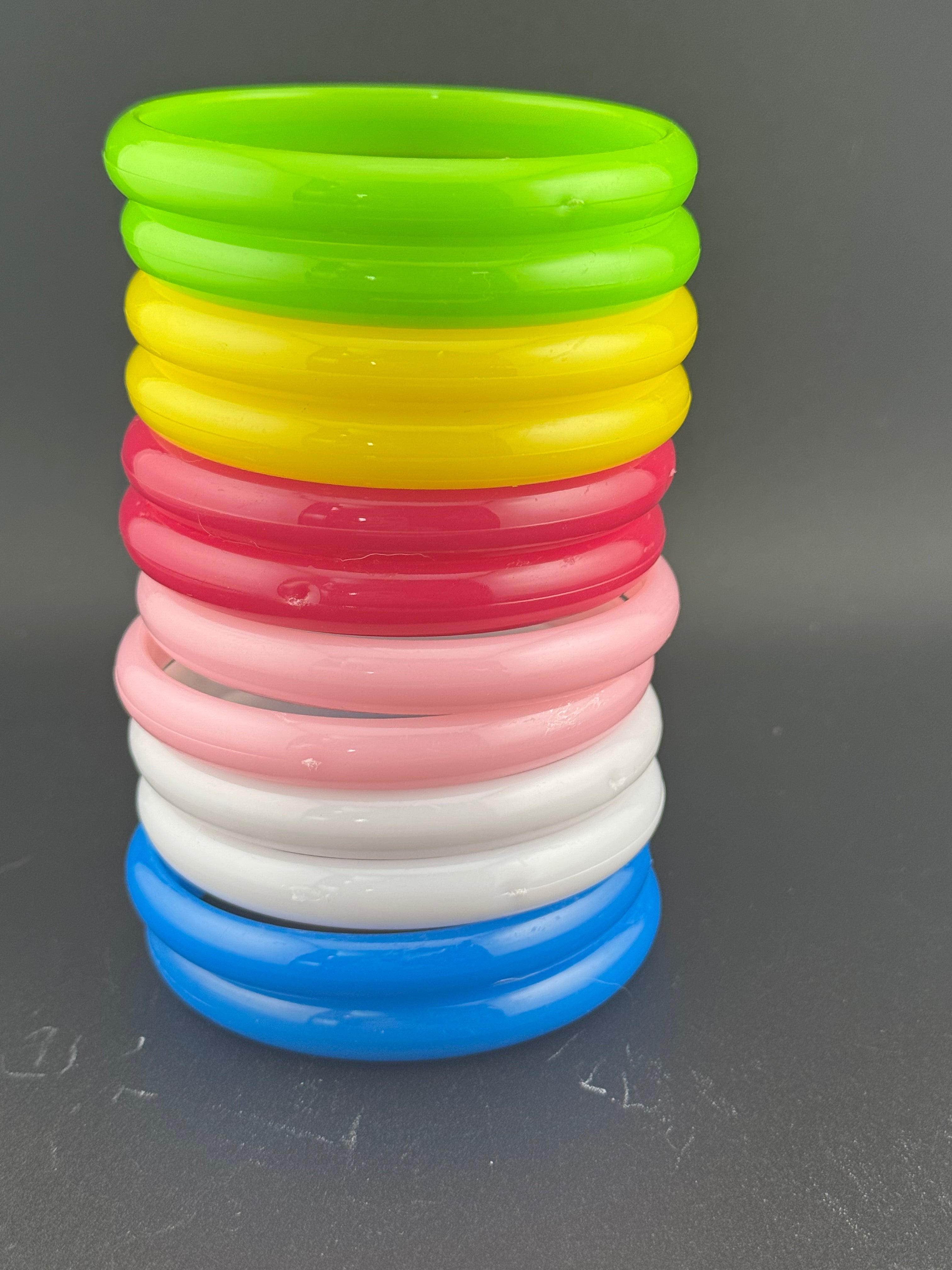 Stack of 12 coloured acrylic stacking bangles in baby pink yellow bright pink blue white green