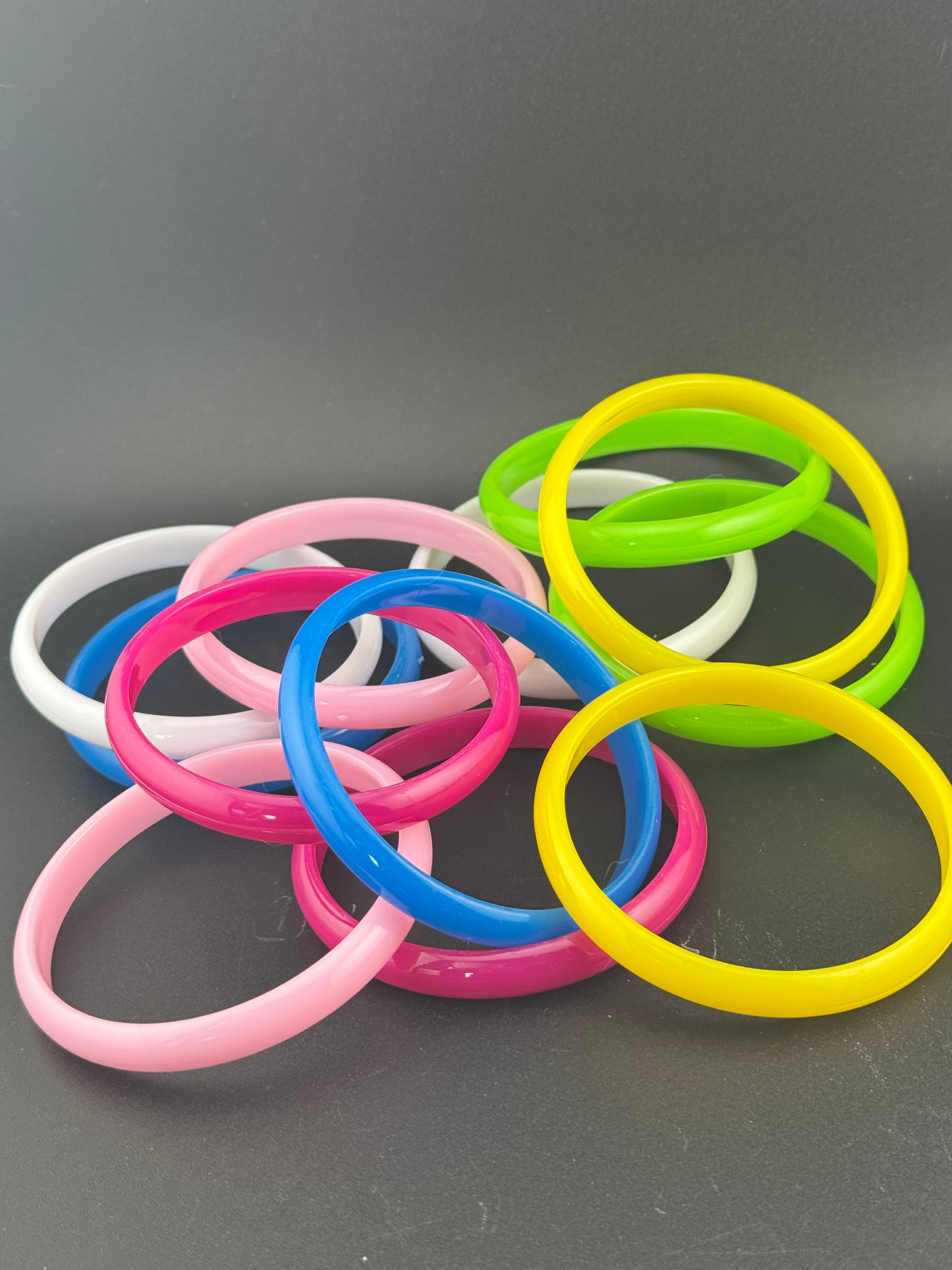 Stack of 12 coloured acrylic stacking bangles in baby pink yellow bright pink blue white green