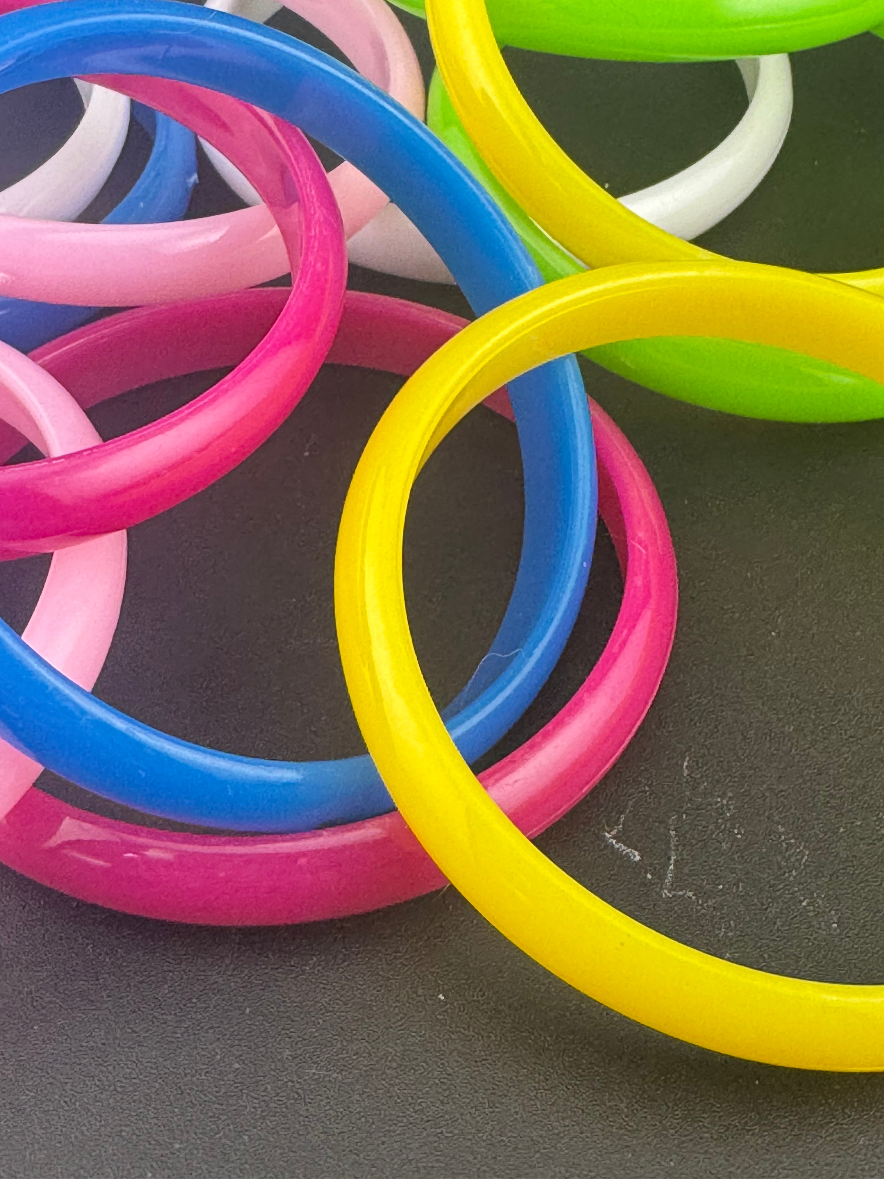 Stack of 12 coloured acrylic stacking bangles in baby pink yellow bright pink blue white green