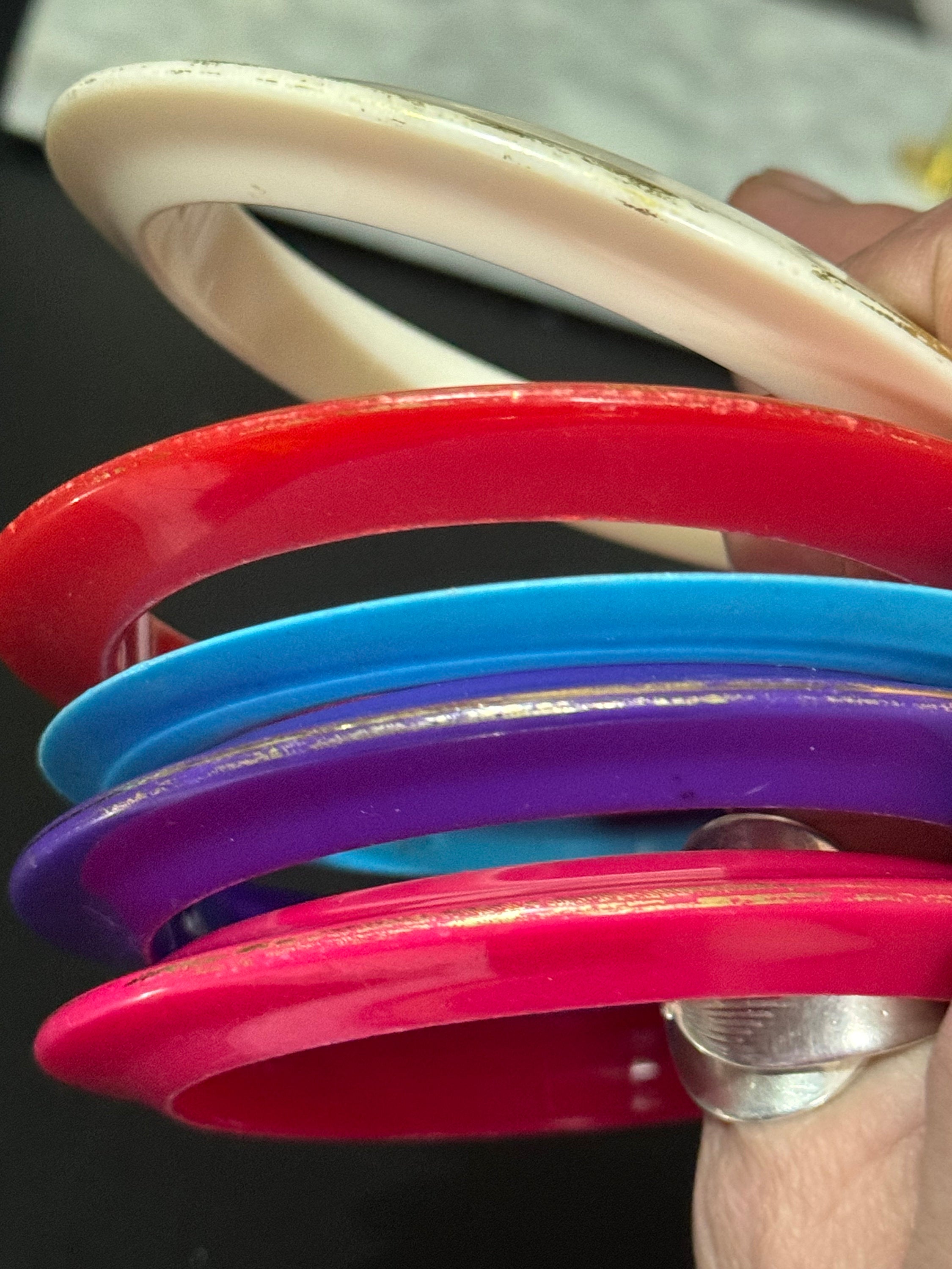 Vintage stack of coloured red purple blue cream pink plastic bangles retro acrylic bracelets